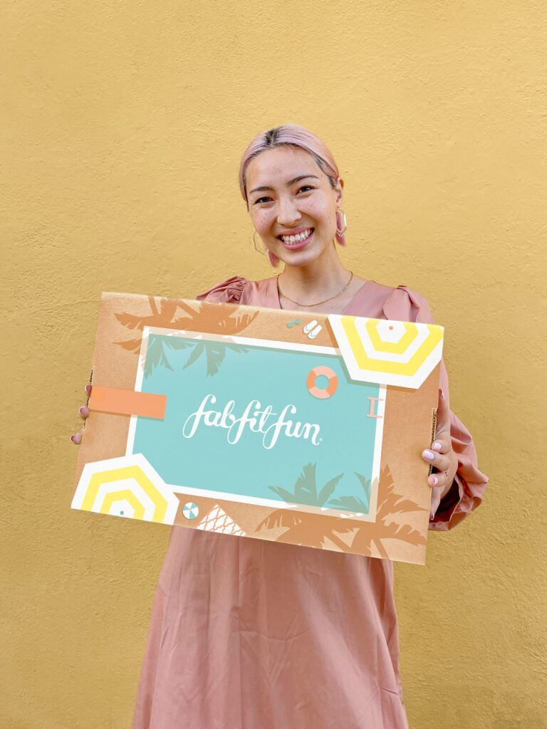Kvinne smilende holder en FabFitFun-boks.