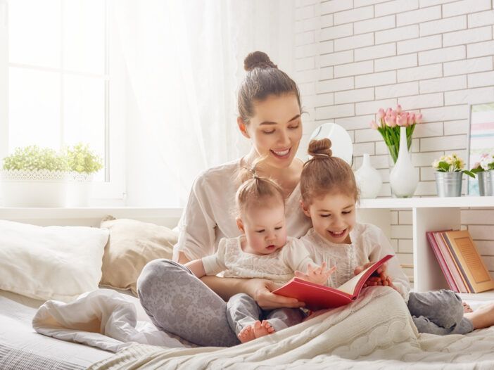 Imagen de una madre joven leyendo a sus hijos