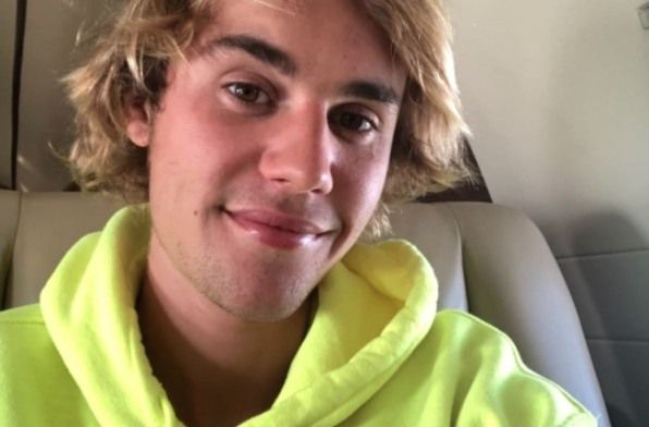 Justin Bieber con cabello largo y sudadera con capucha amarilla