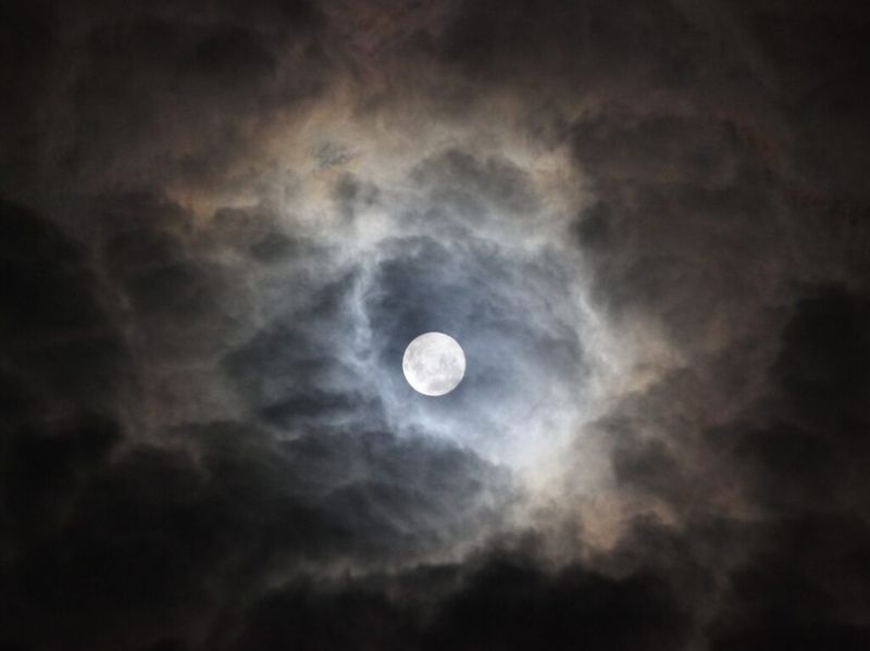 En fullmåne bak et tynt lag med skyer på nattehimmelen