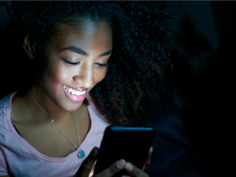 Portrét uvoľneného čierneho dievčaťa pomocou telefónu v noci