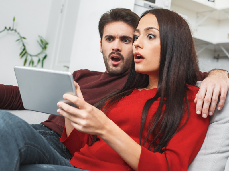 Genç çift evde romantik bir akşam geçiriyor, dijital tablete göz atıyor.